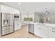 Open-concept kitchen boasts stainless steel appliances, quartz countertops, island with sink, and eat in dining area at 12913 County Road 104B, Oxford, FL 34484