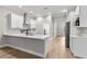 Modern kitchen boasts stainless appliances, white cabinets, quartz countertops, stainless vent hood, and a kitchen island at 12913 County Road 104B, Oxford, FL 34484