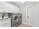 Functional laundry room with front-load washer and dryer, sink, and ample cabinet space at 12913 County Road 104B, Oxford, FL 34484