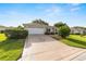 Well maintained driveway and front exterior of a home with manicured lawn and mature shrubbery at 13643 Se 89Th Ct, Summerfield, FL 34491