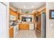 Bright kitchen with tile flooring, stainless refrigerator, and wooden cabinetry at 13643 Se 89Th Ct, Summerfield, FL 34491