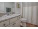 Neat bathroom with granite countertops, a white vanity, and a shower with a textured curtain at 1406 Zest Ave, The Villages, FL 32163