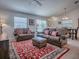 Open-concept living room with plush seating, a decorative rug, and a dining area, creating a warm and inviting space at 1406 Zest Ave, The Villages, FL 32163