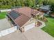 Elevated view displaying the house with solar panels, driveway, backyard, and verdant surroundings at 15664 Se 97Th Ave, Summerfield, FL 34491