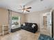 Bedroom features a dark sofa and window with curtains, ceiling fan, and tiled floor at 15664 Se 97Th Ave, Summerfield, FL 34491
