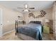A comfortable bedroom with a bed, ceiling fan, side table and decorative wall hangings at 15664 Se 97Th Ave, Summerfield, FL 34491