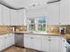 Bright kitchen featuring white cabinetry, granite counters, stainless steel appliances, and a sunlit window overlooking the backyard at 15664 Se 97Th Ave, Summerfield, FL 34491