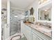 This bathroom features a beautifully tiled glass shower and granite counters with elegant white cabinetry at 17380 Se 111Th Ct, Summerfield, FL 34491