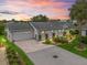 Charming single-story home with a two-car garage, brick driveway, and beautifully landscaped front yard during sunset at 17380 Se 111Th Ct, Summerfield, FL 34491