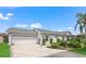 Charming home features a two-car garage, brick driveway and walkway, trimmed bushes, and landscaped flower beds at 17380 Se 111Th Ct, Summerfield, FL 34491