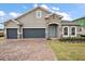 Beautiful single-Gathering home featuring a two-car garage, paver driveway, manicured lawn, and a charming stone facade at 1849 Sunshine Peak Dr, Minneola, FL 34715