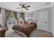 Bedroom features a cozy bed, shuttered windows, elegant ceiling fan, and neutral decor at 1956 Brantley Cir, Clermont, FL 34711