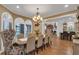 Open-concept dining room with a wood table set for six, chandelier, and arched windows at 1956 Brantley Cir, Clermont, FL 34711