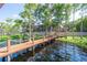 Inviting wooden dock with rope railings leads to a luxurious waterfront home with a screened-in porch at 1956 Brantley Cir, Clermont, FL 34711
