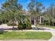Beautiful brick home with mature trees, lush landscaping, and a long driveway leading to the entrance at 1956 Brantley Cir, Clermont, FL 34711
