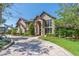 Elegant brick home with arched entryway, manicured landscaping, and a circular brick driveway at 1956 Brantley Cir, Clermont, FL 34711