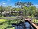 Exterior view showcasing a home with a screened-in pool, lush greenery, and a private dock at 1956 Brantley Cir, Clermont, FL 34711