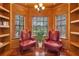Cozy sitting room with wood-paneled walls, built-in bookshelves, natural light, and two comfortable red chairs at 1956 Brantley Cir, Clermont, FL 34711