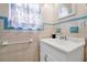 Bathroom with white vanity, blue tiled trim, and a window with blue patterned curtains at 2007 Mosher Dr, Orlando, FL 32810
