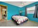 Bright blue bedroom featuring terrazzo floors, ceiling fan, and a comfortable bed with a cozy quilt at 2007 Mosher Dr, Orlando, FL 32810