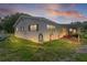 The exterior of the home features a covered patio area and lush green lawn at dusk at 2022 Edgewood Rd, Leesburg, FL 34748