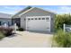 Charming gray home with a white garage door, white picket fence, and lush green landscaping at 2142 Weber Ct, The Villages, FL 32163