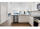 Bright kitchen features stainless steel appliances, white cabinets, and wood floors, open to the living room at 2142 Weber Ct, The Villages, FL 32163