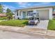 Charming single-story home featuring a lush lawn, tidy landscaping, a white exterior and a golf cart parked in the driveway at 2235 Harbor Town Ln, Lakeland, FL 33810
