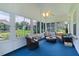 Bright sunroom with full windows, comfortable seating, and lush green backyard views at 2738 Morven Park Way, The Villages, FL 32162
