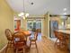 Bright dining area with wood floors, chandelier, and wood table with chairs is adjacent to the kitchen at 2766 Privada Dr, The Villages, FL 32162