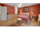 Interior of main bedroom with red walls, light wood floors and ensuite bath at 2766 Privada Dr, The Villages, FL 32162