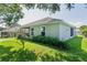 Back exterior view of home featuring a screened-in porch and well-maintained lawn with greenery at 2821 Mediterranean Loop, Tavares, FL 32778