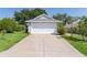 Home featuring a spacious driveway leading to an attached two-car garage and front yard with mature landscaping at 2821 Mediterranean Loop, Tavares, FL 32778