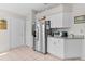 Kitchen with stainless steel refrigerator, white cabinetry, and tiled floor near pantry and entry door at 2821 Mediterranean Loop, Tavares, FL 32778