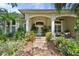 Welcoming front entrance with lush landscaping, white pillars, and comfortable outdoor seating area at 2904 Avalos Dr, The Villages, FL 32162