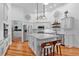 Modern white kitchen with center island, pendant lighting, stainless steel appliances, and hardwood floors at 2904 Avalos Dr, The Villages, FL 32162