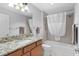 Bathroom with a granite vanity, built-in tub and shower with a white curtain at 2967 Thayer Ter, The Villages, FL 32163