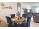 Dining area features round wood table, tufted dining chairs, and view into the living room at 3181 Hill Point St, Minneola, FL 34715