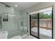 Updated bathroom featuring a glass enclosed shower, toilet, neutral decor, and sliding glass doors to the outside patio at 33 Palm Dr, Yalaha, FL 34797