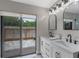Modern bathroom with a double sink vanity, stylish lighting, and a sliding glass door to the patio at 33 Palm Dr, Yalaha, FL 34797