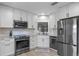Updated kitchen with white cabinets, stainless steel appliances, and modern backsplash at 33 Palm Dr, Yalaha, FL 34797