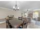 Open-concept living and dining area featuring a stylish chandelier, comfortable seating, and a large screen television at 33 Palm Dr, Yalaha, FL 34797
