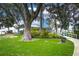 Lush green lawn with mature trees and landscaped garden leading to a charming waterfront property at 33 Palm Dr, Yalaha, FL 34797