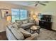 Cozy living room featuring comfortable sofas, natural light, area rug, and dark entertainment center at 3337 Candlebrook St, The Villages, FL 32162
