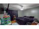 Bedroom featuring hardwood floors, ceiling fan, and mounted TV with blackout curtains at 33913 Sabal Way, Leesburg, FL 34748