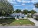 Charming single-story home features a well-manicured lawn, mature trees, and a welcoming entrance with a blue door at 33913 Sabal Way, Leesburg, FL 34748