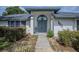 Inviting front entrance with a blue door, manicured bushes, and a cozy seating area at 33913 Sabal Way, Leesburg, FL 34748