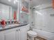 Clean bathroom featuring a vanity with granite countertop, a tub with glass doors, and nautical decor at 3425 S Atlantic Ave # 1101, Daytona Beach, FL 32118