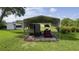A tractor and trailer sit protected underneath a sturdy metal carport on a grassy lawn at 36535 Eagle Dr, Grand Island, FL 32735