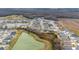 An aerial shot showing a pond and homes in a community near a golf course and wooded area at 3769 Causey Ct, The Villages, FL 32163